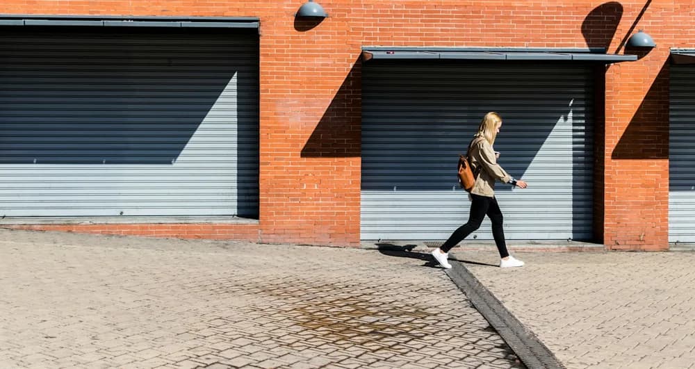 A pedestrian walking along a sunlit city street