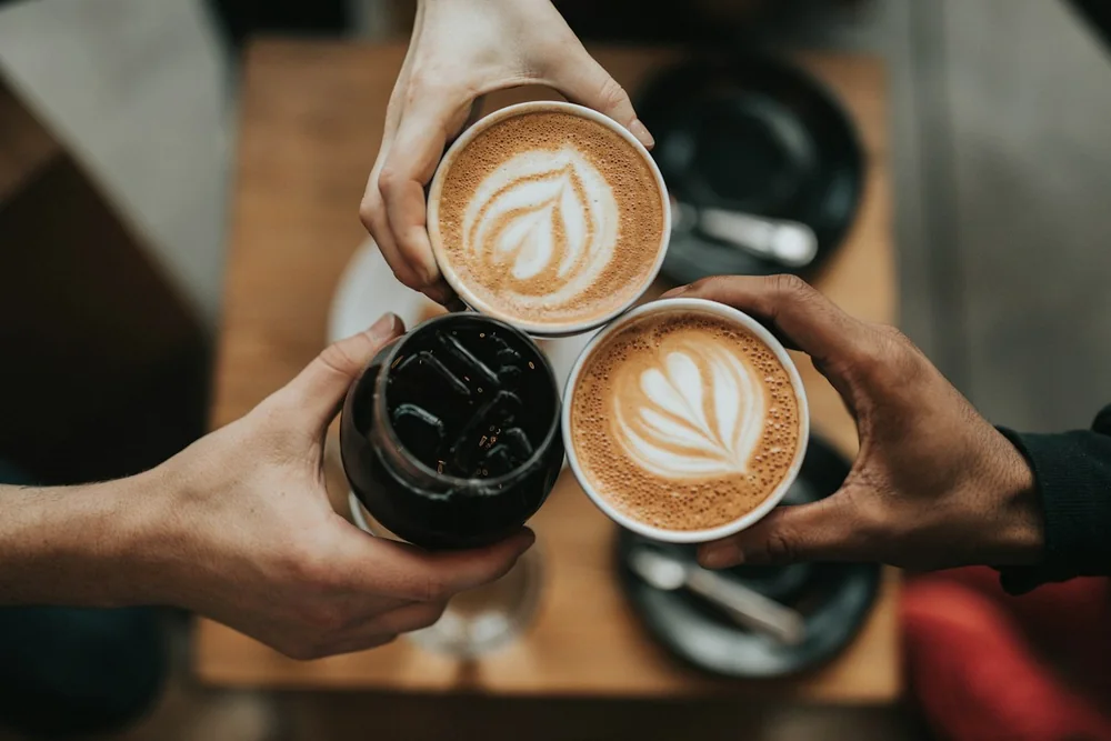Three hands bringing coffee cups together
